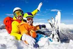 Dad and son skiers sit in snow on mountain top Royalty Free Stock Images Dad and son skiers sit in snow on mountain top Royalty Free Stock Images