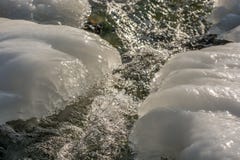 Daggvattenflöden ner ett berg med ett tjockt lager av is på kusten arkivfoto Daggvattenflöden ner ett berg med ett tjockt lager av is på kusten arkivfoto