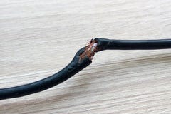 Damaged black electric cord on wooden table or floor background. Dangerous broken electrical cable stock images Damaged black electric cord on wooden table or floor background. Dangerous broken electrical cable stock images