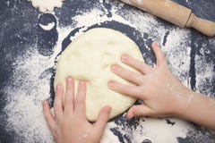 Danandedeg för litet barn för att dra tillbaka Händer för unge` s, några pudrar, vetedeg och kavlen på den svarta tabellen Barnha arkivfoton Danandedeg för litet barn för att dra tillbaka Händer för unge` s, några pudrar, vetedeg och kavlen på den svarta tabellen Barnha arkivfoton