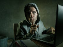 Dangerous looking young hacker man in hoodie typing on laptop computer hacking and decoding system data or having illegal access b royalty free stock photos Dangerous looking young hacker man in hoodie typing on laptop computer hacking and decoding system data or having illegal access b royalty free stock photos