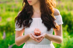 Dark haired young girl holding a pink-creamed muffin royalty free stock photo Dark haired young girl holding a pink-creamed muffin royalty free stock photo