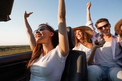 Dark-haired young woman dressed in a white t-shirt is sitting a black cabriolet with friends on a summer day. stock images Dark-haired young woman dressed in a white t-shirt is sitting a black cabriolet with friends on a summer day. stock images