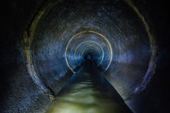 Dark underground sewer round concrete tunnel. Industrial wastewater and urban sewage flowing throw sewer pipe