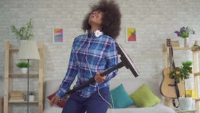 Das ausdrucksvolle positive Hausfraustaubsaugen der jungen Frau des Afroamerikaners singt Spaßtanzen und das Spielen der eingebil stock video Das ausdrucksvolle positive Hausfraustaubsaugen der jungen Frau des Afroamerikaners singt Spaßtanzen und das Spielen der eingebil stock video