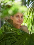 Das Mädchen versteckte sich hinter den Palmblättern lizenzfreies stockfoto Das Mädchen versteckte sich hinter den Palmblättern lizenzfreies stockfoto