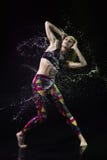 Das Mädchen tanzt auf den Boden, der mit Wasser auf einem schwarzen Hintergrund bedeckt wird und Wasser spritzt um sie stockfoto Das Mädchen tanzt auf den Boden, der mit Wasser auf einem schwarzen Hintergrund bedeckt wird und Wasser spritzt um sie stockfoto