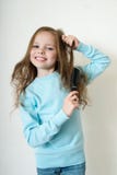 Das nette lächelnde kleine Mädchen, das ihren Haarkamm kämmt, stellt Haar her lizenzfreie stockfotos Das nette lächelnde kleine Mädchen, das ihren Haarkamm kämmt, stellt Haar her lizenzfreie stockfotos