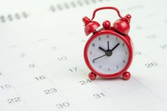 Date and time reminder or deadline concept, small red alarm clock on white clean calendar with number of day, counting down to
