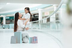 Daughter is sitting on mother`s lap in shopping mall. Mom and girl are smiling. stock photo Daughter is sitting on mother`s lap in shopping mall. Mom and girl are smiling. stock photo