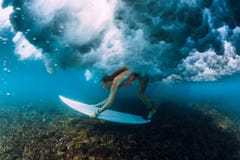 De aantrekkelijke surfervrouw duikt onder verpletterende vatgolf stock fotografie De aantrekkelijke surfervrouw duikt onder verpletterende vatgolf stock fotografie