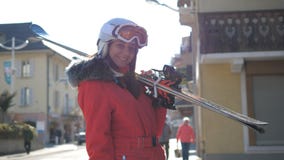 De aantrekkelijke Vrouw bevindt zich dichtbij Huizen bergaf Houdend Haar Ski Before Skiing stock foto's De aantrekkelijke Vrouw bevindt zich dichtbij Huizen bergaf Houdend Haar Ski Before Skiing stock foto's