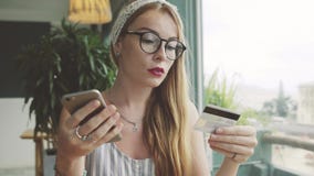 De aantrekkelijke vrouw maakt aankopen met creditcard en cellphone Wijfje die online in koffie winkelen stock videobeelden De aantrekkelijke vrouw maakt aankopen met creditcard en cellphone Wijfje die online in koffie winkelen stock videobeelden