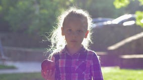 De appel van kindbeten in backlight, meisje gekleed overhemd kauwt sappig rijp fruit en bekijkt op camera aard stock videobeelden De appel van kindbeten in backlight, meisje gekleed overhemd kauwt sappig rijp fruit en bekijkt op camera aard stock videobeelden