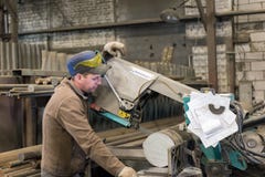 De arbeider maakt het zagen van het metaalwerkstuk op een lintzaag stock afbeelding De arbeider maakt het zagen van het metaalwerkstuk op een lintzaag stock afbeelding