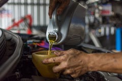 De autowerktuigkundige vult een verse olie van de smeermiddelmotor royalty-vrije stock fotografie De autowerktuigkundige vult een verse olie van de smeermiddelmotor royalty-vrije stock fotografie