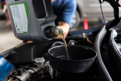 De autowerktuigkundige vult een verse olie van de smeermiddelmotor stock afbeelding De autowerktuigkundige vult een verse olie van de smeermiddelmotor stock afbeelding