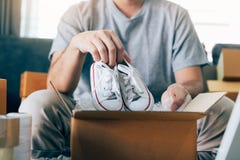 De Aziatische ondernemerstiener draagt babyschoenen en wordt gezet in een klant van de kartondoos om het product thuis te leveren stock afbeeldingen De Aziatische ondernemerstiener draagt babyschoenen en wordt gezet in een klant van de kartondoos om het product thuis te leveren stock afbeeldingen