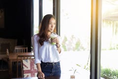 De Aziatische vrouwen drinken koffie en kijken buiten stock fotografie De Aziatische vrouwen drinken koffie en kijken buiten stock fotografie