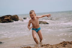 De babyjongen stelt uit de emotiesgelach in werking van het waterstrand royalty-vrije stock afbeeldingen De babyjongen stelt uit de emotiesgelach in werking van het waterstrand royalty-vrije stock afbeeldingen