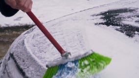 De bestuurder ontruimt de auto van de sneeuw De bestuurder ontruimt de auto van de sneeuw
