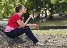 De blazende bellen van de vrouw in park stock afbeeldingen De blazende bellen van de vrouw in park stock afbeeldingen