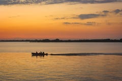 De bootzeilen op kalm water bij zonsondergang royalty-vrije stock fotografie De bootzeilen op kalm water bij zonsondergang royalty-vrije stock fotografie