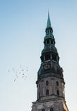 De bovenkant van een clocktower met groene bovenkant en vogels die daarna het vliegen royalty-vrije stock foto De bovenkant van een clocktower met groene bovenkant en vogels die daarna het vliegen royalty-vrije stock foto