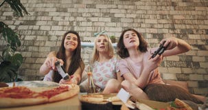 De charismatische dames in pyjama's hebben een prettijd die samen op een PlayStation-close-up voor de camera op spelen stock video De charismatische dames in pyjama's hebben een prettijd die samen op een PlayStation-close-up voor de camera op spelen stock video