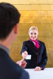 De controle van de hotelreceptionnist bij de mens die zeer belangrijke kaart geven royalty-vrije stock foto's De controle van de hotelreceptionnist bij de mens die zeer belangrijke kaart geven royalty-vrije stock foto's