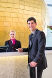 De controle van de hotelreceptionnist bij de mens die zeer belangrijke kaart geven stock afbeeldingen De controle van de hotelreceptionnist bij de mens die zeer belangrijke kaart geven stock afbeeldingen