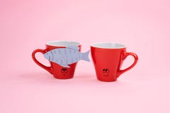De Dagviering van April Fools ‚, document vissenstreek Twee het gekscheren het lachen koffiekoppen met document vissen op roze ac stock foto De Dagviering van April Fools ‚, document vissenstreek Twee het gekscheren het lachen koffiekoppen met document vissen op roze ac stock foto