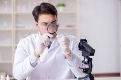 De deskundige criminoloog die in het laboratorium voor bewijsmateriaal werken stock afbeelding De deskundige criminoloog die in het laboratorium voor bewijsmateriaal werken stock afbeelding