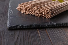 De droge noedels van boekweitsoba op rustieke houten raad stock fotografie De droge noedels van boekweitsoba op rustieke houten raad stock fotografie
