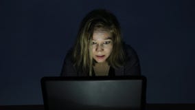 De ernstige jonge vrouw die computer in een donkere ruimte met behulp van, bekijkt de monitor en begint boos te worden stock footage De ernstige jonge vrouw die computer in een donkere ruimte met behulp van, bekijkt de monitor en begint boos te worden stock footage