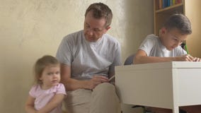 De familietijd van de vader - lezing voor dochter, die zoon helpen stock footage De familietijd van de vader - lezing voor dochter, die zoon helpen stock footage