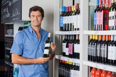 De Fles van de mensenholding Alcohol bij Supermarkt stock afbeelding De Fles van de mensenholding Alcohol bij Supermarkt stock afbeelding