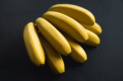 De gele heldere rijpe bananen liggen op een zwarte achtergrond Heerlijke banaantak fruit op een zwarte achtergrond stock afbeeldingen De gele heldere rijpe bananen liggen op een zwarte achtergrond Heerlijke banaantak fruit op een zwarte achtergrond stock afbeeldingen