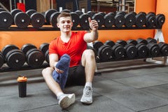 De gelukkige aantrekkelijke mens die na een training rusten en toont zijn duim bij de gymnastiek stock foto De gelukkige aantrekkelijke mens die na een training rusten en toont zijn duim bij de gymnastiek stock foto