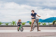 De gelukkige familie berijdt in openlucht fietsen en glimlacht Vader op B royalty-vrije stock afbeeldingen De gelukkige familie berijdt in openlucht fietsen en glimlacht Vader op B royalty-vrije stock afbeeldingen