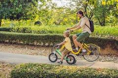 De gelukkige familie berijdt in openlucht fietsen en glimlacht Vader op een fiets en zoon op een balancebike stock fotografie De gelukkige familie berijdt in openlucht fietsen en glimlacht Vader op een fiets en zoon op een balancebike stock fotografie