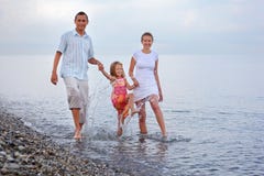 De gelukkige familie bespat voetenwater op strand stock afbeeldingen De gelukkige familie bespat voetenwater op strand stock afbeeldingen