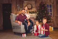 De gelukkige familiezitting met Kerstmis stelt en kijkend voor stock afbeeldingen De gelukkige familiezitting met Kerstmis stelt en kijkend voor stock afbeeldingen