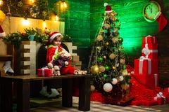 De gelukkige jongen speelt met speelgoed door de Kerstboom r Het jonge geitje wacht op Nieuw royalty-vrije stock foto's De gelukkige jongen speelt met speelgoed door de Kerstboom r Het jonge geitje wacht op Nieuw royalty-vrije stock foto's