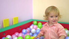 De gelukkige leuke peuter die van het babymeisje en in multi gekleurde balpool glimlachen spelen peuter stock footage De gelukkige leuke peuter die van het babymeisje en in multi gekleurde balpool glimlachen spelen peuter stock footage