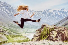 De gelukkige vrouw springt bergenreis Stock Afbeelding De gelukkige vrouw springt bergenreis Stock Afbeelding