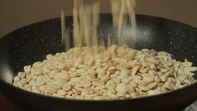 De gepelde pinda's zijn gebraden in een pan Hand met lepel het bewegen noten stock footage De gepelde pinda's zijn gebraden in een pan Hand met lepel het bewegen noten stock footage
