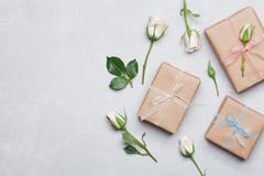 De gift of het huidige vakje verpakte in kraftpapier-document en nam hierboven bloem op grijze lijst toe van Vlak leg het stilere royalty-vrije stock afbeelding De gift of het huidige vakje verpakte in kraftpapier-document en nam hierboven bloem op grijze lijst toe van Vlak leg het stilere royalty-vrije stock afbeelding