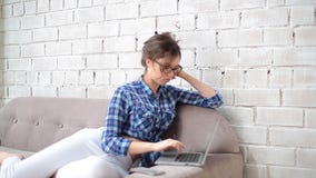 De glazen en het begin die van de meisjes freelancer kleding aan laptop thuis werken Zij is gekleed in witte jeans en een blauwe stock videobeelden De glazen en het begin die van de meisjes freelancer kleding aan laptop thuis werken Zij is gekleed in witte jeans en een blauwe stock videobeelden