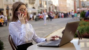 De glimlachende aantrekkelijke dame met rode lippen spreekt op haar cel telefoon en het gebruiken van haar laptop stock video De glimlachende aantrekkelijke dame met rode lippen spreekt op haar cel telefoon en het gebruiken van haar laptop stock video